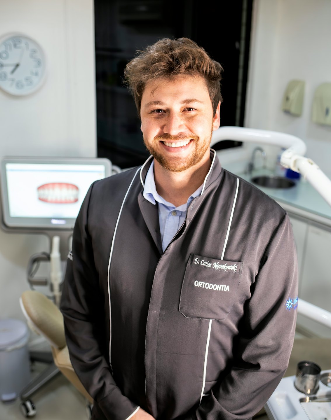 Gülümseyen bir diş hekimi modern bir diş kliniğinde 3D modeli inceliyor.