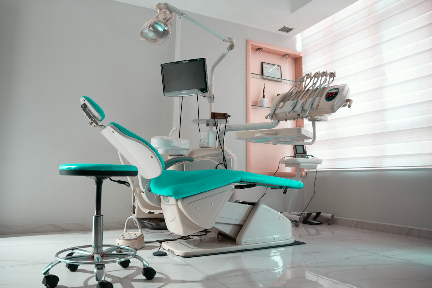 Temiz bir klinikte modern turkuaz dişçi koltuğu ve ekipmanları.
